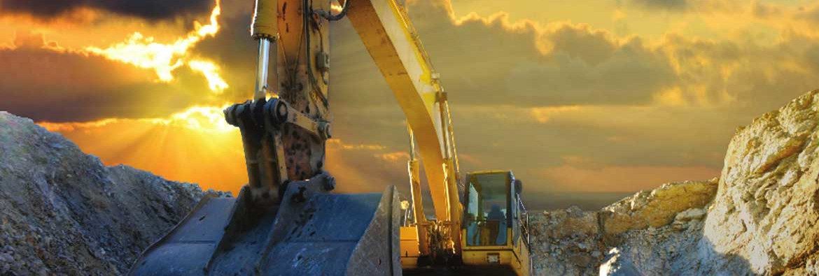 Lydford Mining Company. An excavator working with the sun behind clouds creating an orange sky.