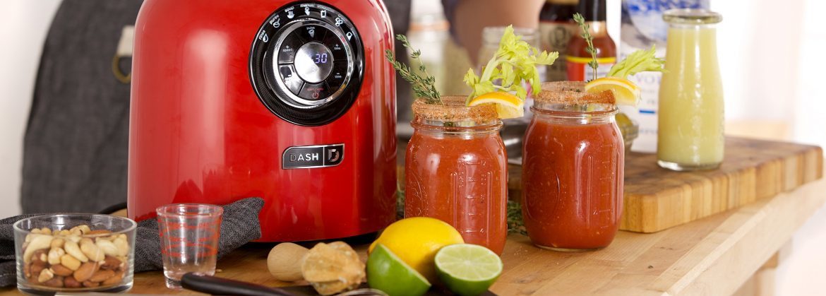 StoreBound. A red blender with bloody mary ingredients on the table and two glass jars with red liquid and celery sticks.