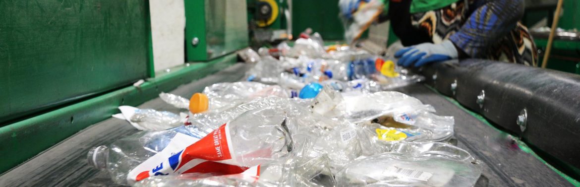 FirstStar Recycling / FirstStar Fiber; a belt of plastic materials and a workers hands visible while they stand at the ready.