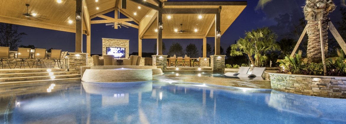 Regal Pools example of a pool with covered seating and a tv behind it.